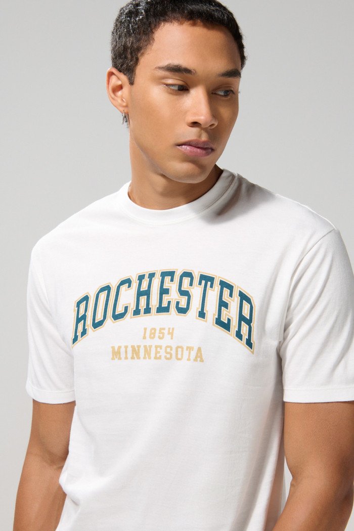 Camiseta crema cuello redondo college con hombro rodado