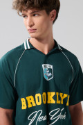 Camiseta verde oscura con diseños college y cuello polo