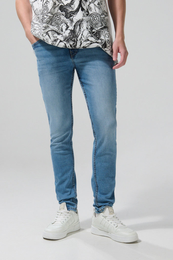 Jean skinny azul medio con desgastes, tiro bajo y bolsillos