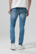 Jean skinny azul medio con desgastes, tiro bajo y bolsillos