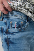 Jean skinny azul medio con desgastes, tiro bajo y bolsillos