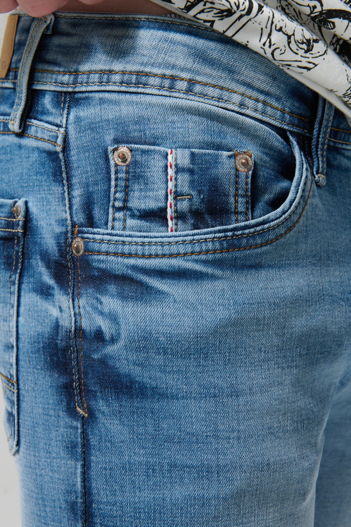 Jean skinny azul medio con desgastes, tiro bajo y bolsillos