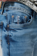 Jean skinny azul medio con desgastes, tiro bajo y bolsillos