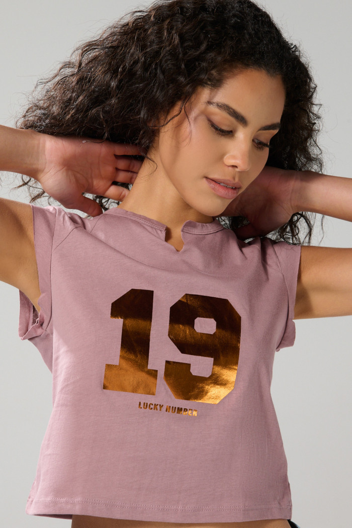 Camiseta rosada con arte college y manga ranglan corta