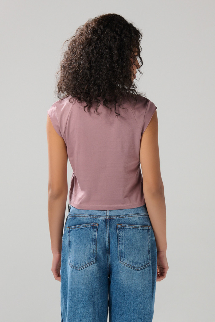 Camiseta rosada con arte college y manga ranglan corta