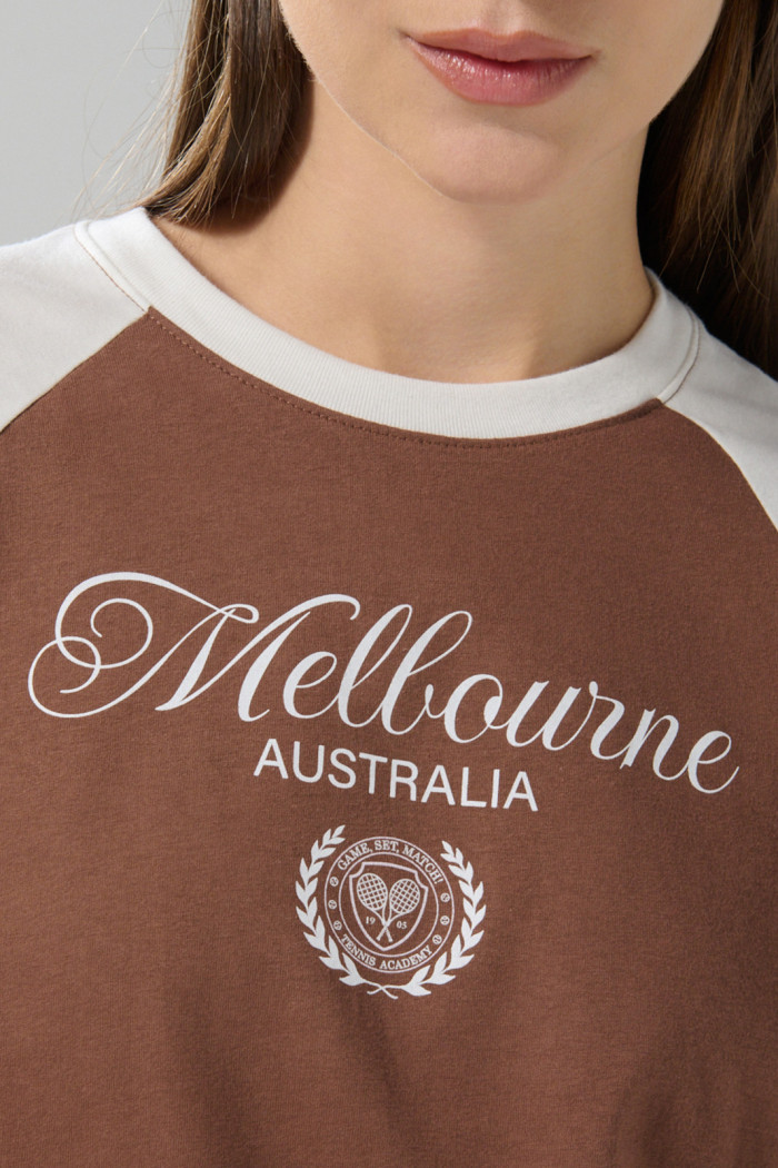 Camiseta café medio con manga ranglan y texto college
