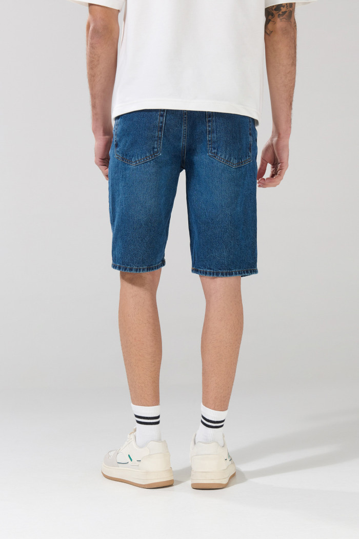 Bermuda de jean slim azul oscura con rotos en frente