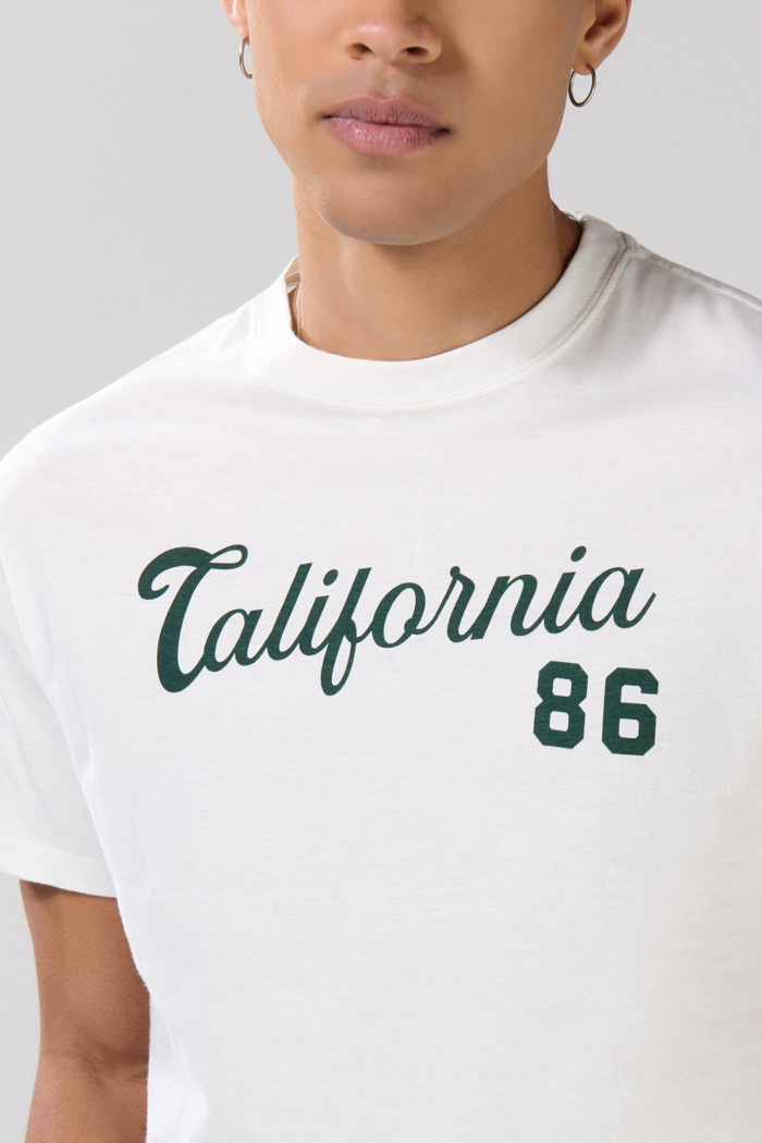 Camiseta crema con texto college en frente y manga corta