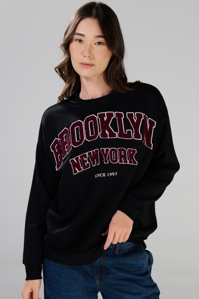 Buzo negro oversize cuello redondo con arte college