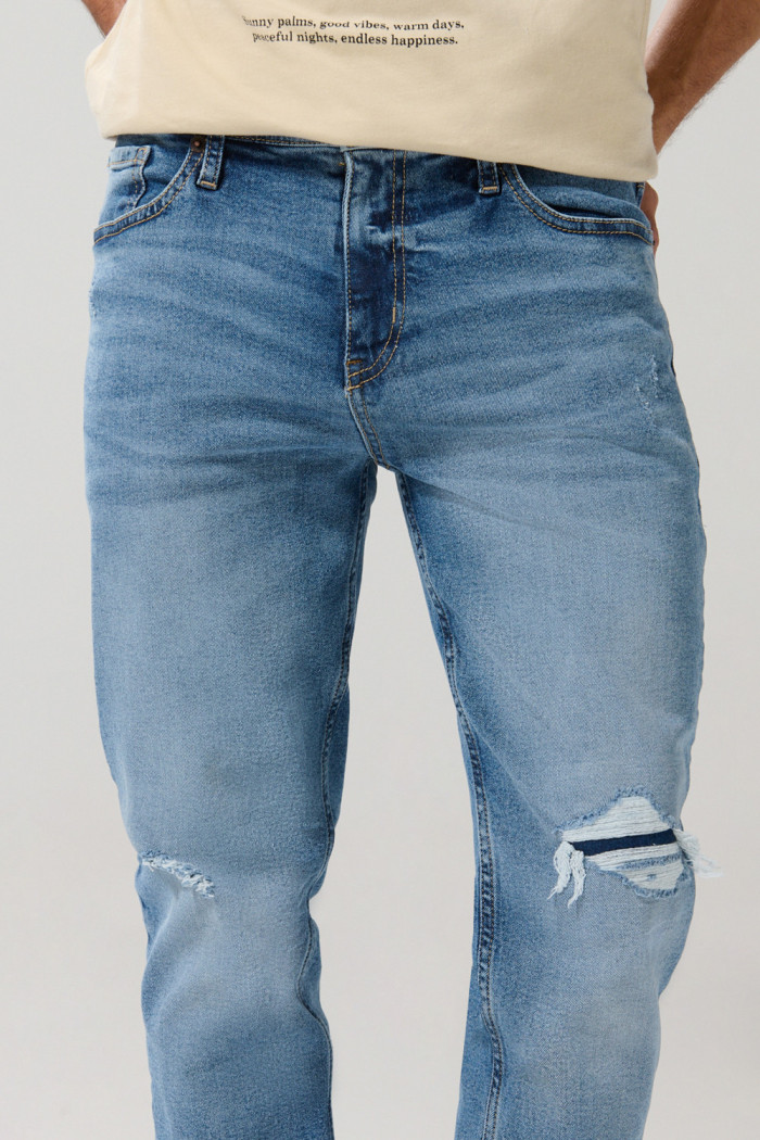 Jean slim azul claro con rotos, tiro bajo y desgastes