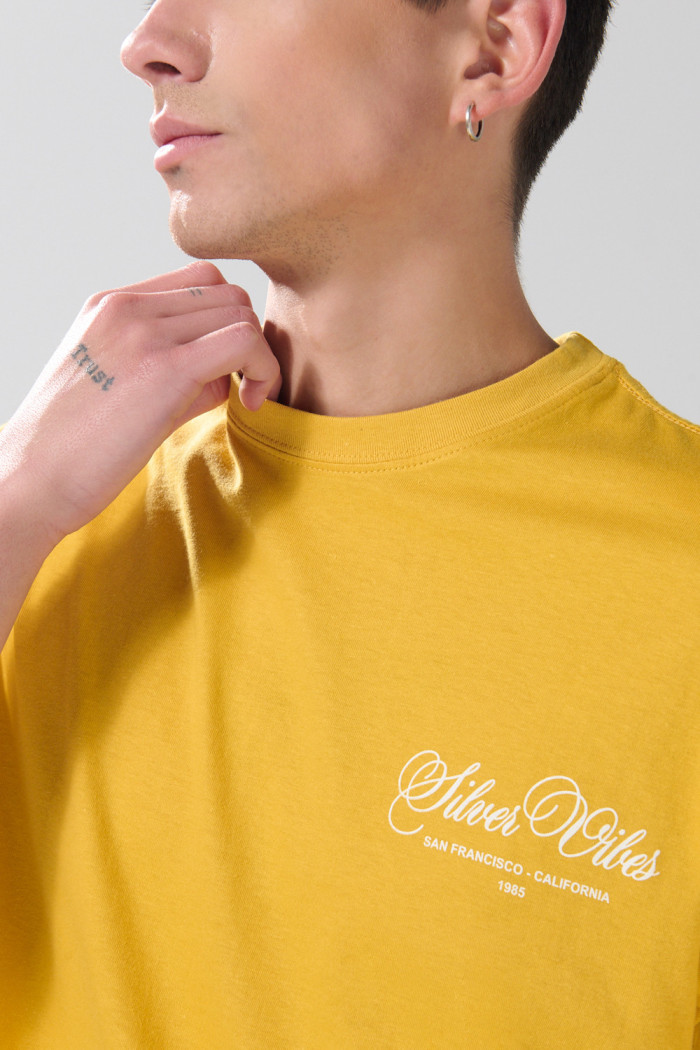Camiseta amarilla oscura manga corta con texto college blanco