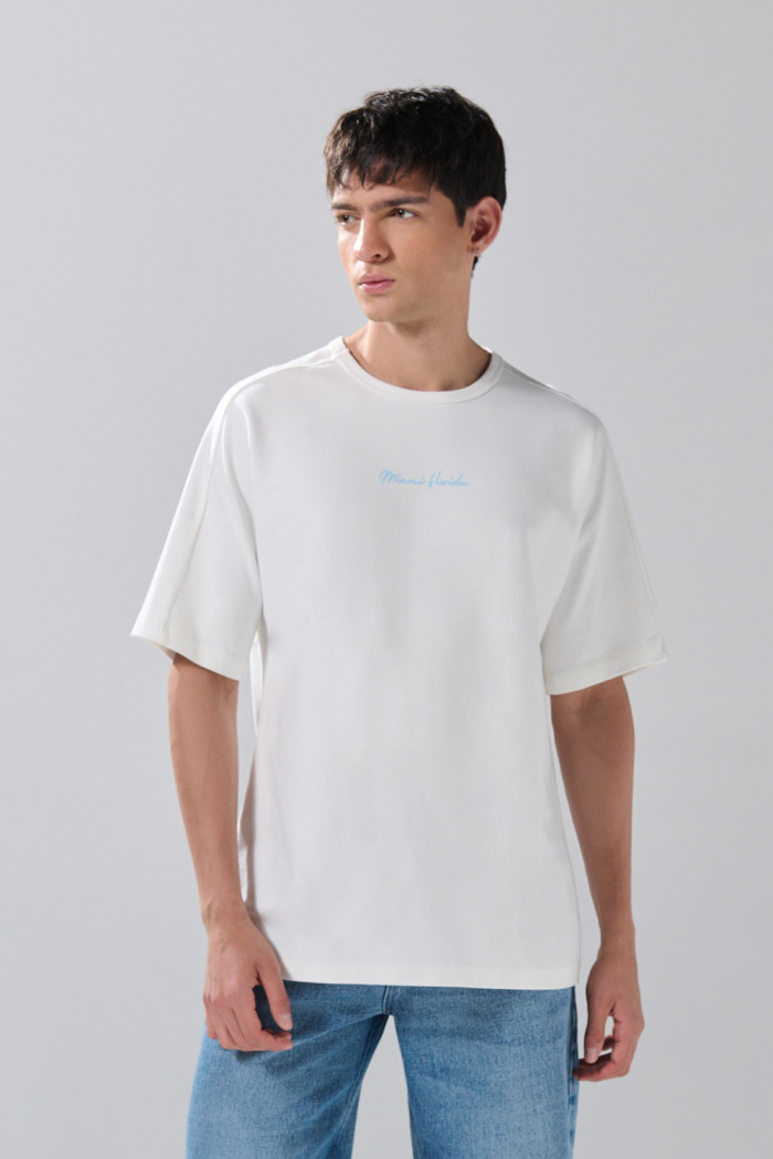 Camiseta crema con manga corta y textos en contraste
