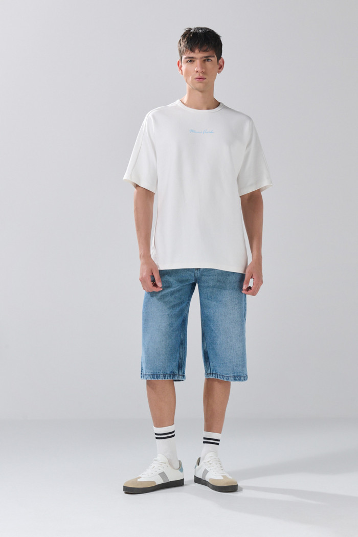 Camiseta crema con manga corta y textos en contraste
