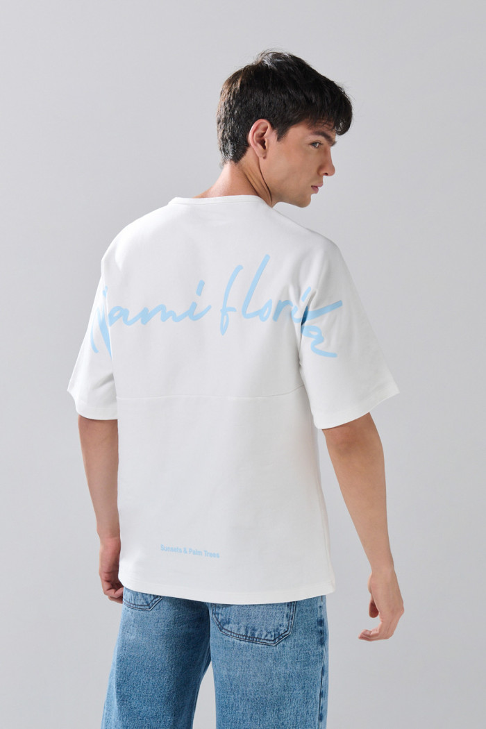 Camiseta crema con manga corta y textos en contraste
