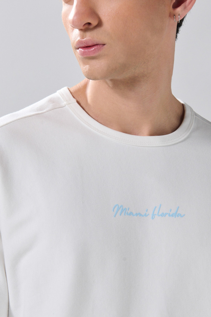 Camiseta crema con manga corta y textos en contraste
