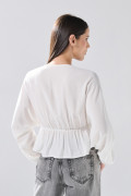 Blusa crema clara con escote en V, recogido y manga larga