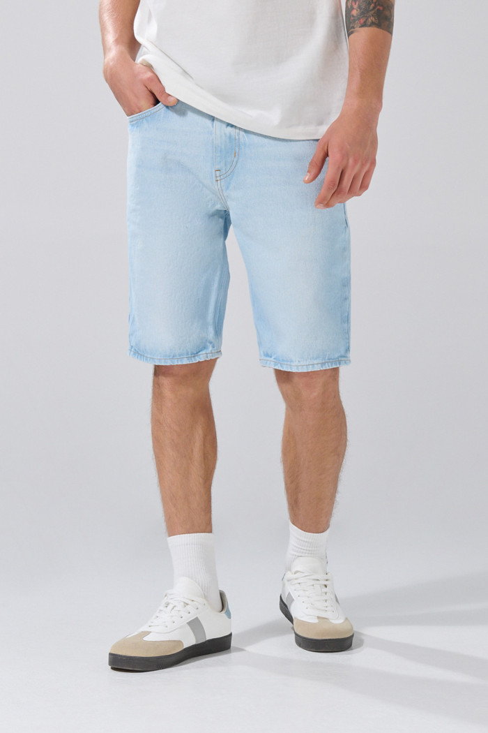 Bermuda azul clara tipo slim con desgastes y tiro bajo