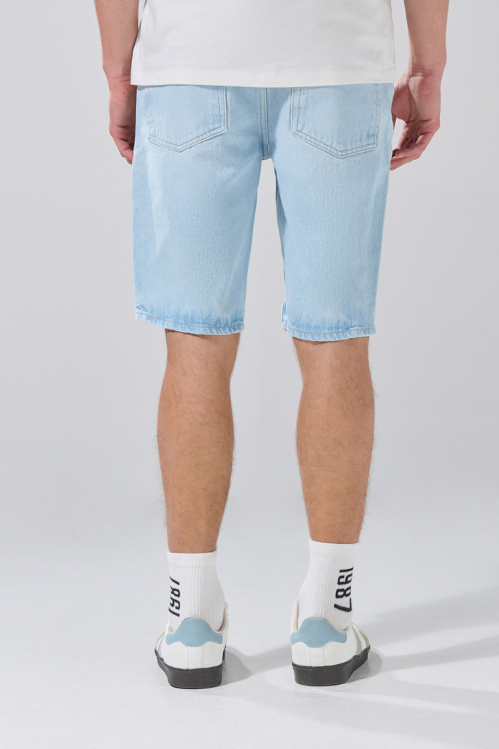 Bermuda azul clara tipo slim con desgastes y tiro bajo