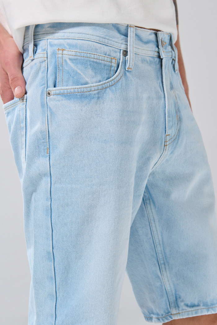 Bermuda azul clara tipo slim con desgastes y tiro bajo