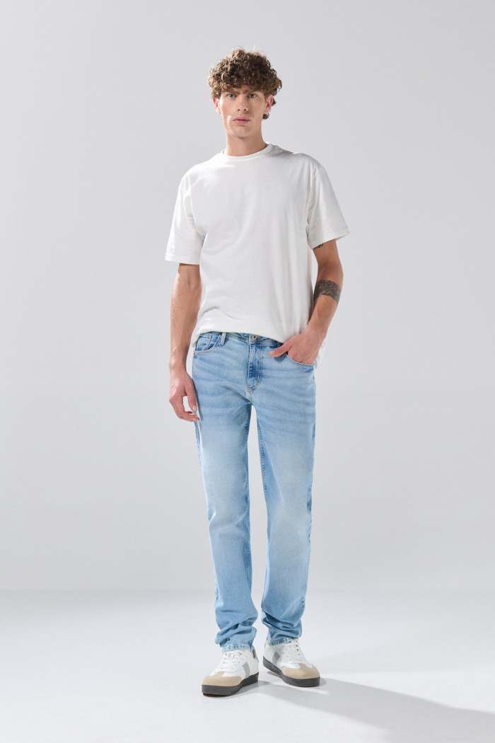Jean slim azul claro con desgastes ligeros y tiro bajo
