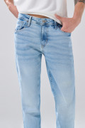 Jean slim azul claro con desgastes ligeros y tiro bajo
