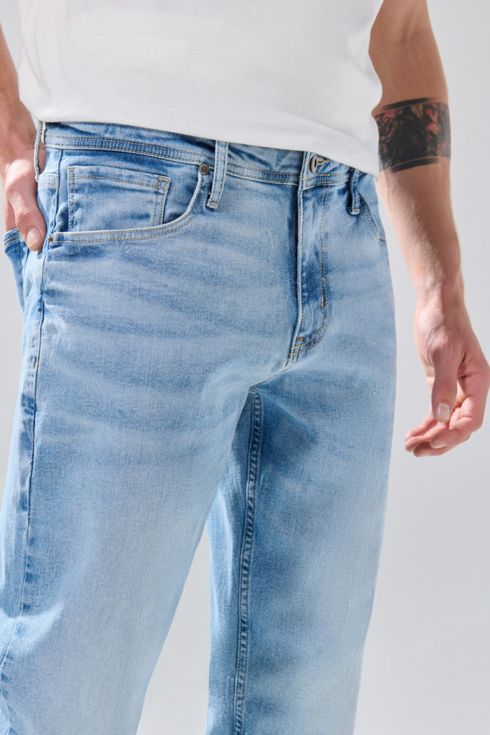 Jean slim azul claro con desgastes ligeros y tiro bajo
