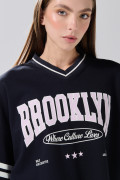 Camiseta crop top azul oversize con cuello V y arte college
