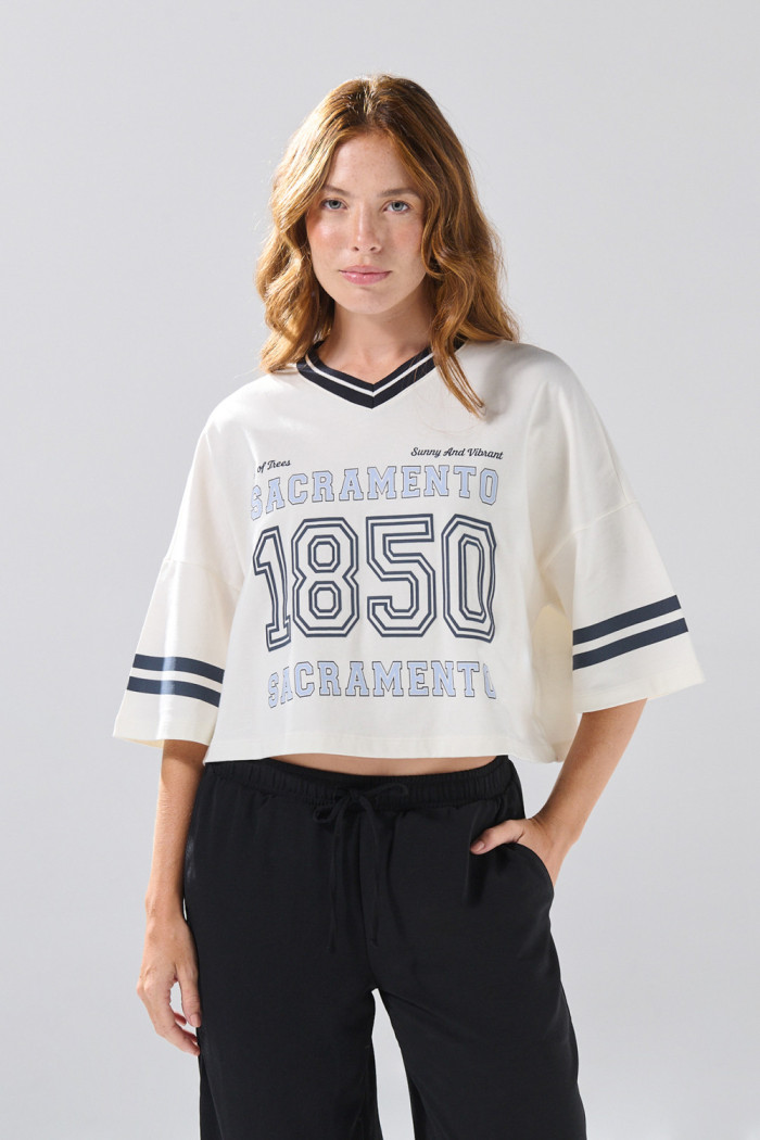 Camiseta oversize crop top crema con cuello V y arte college
