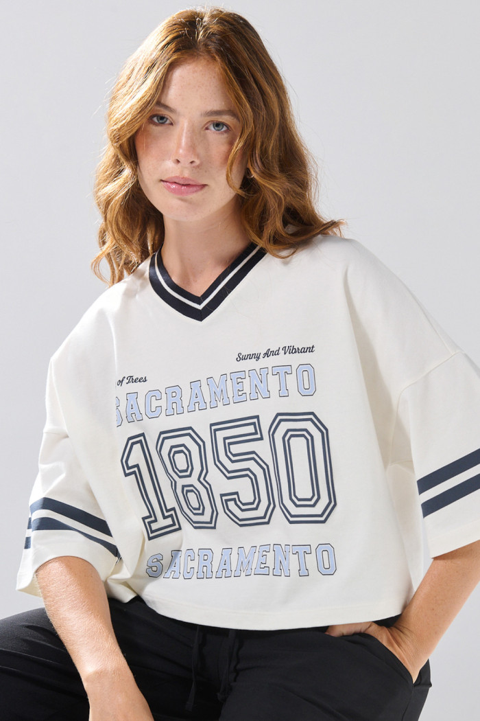 Camiseta oversize crop top crema con cuello V y arte college
