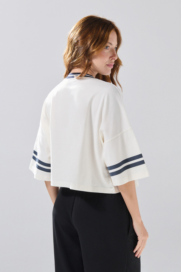 Camiseta oversize crop top crema con cuello V y arte college

