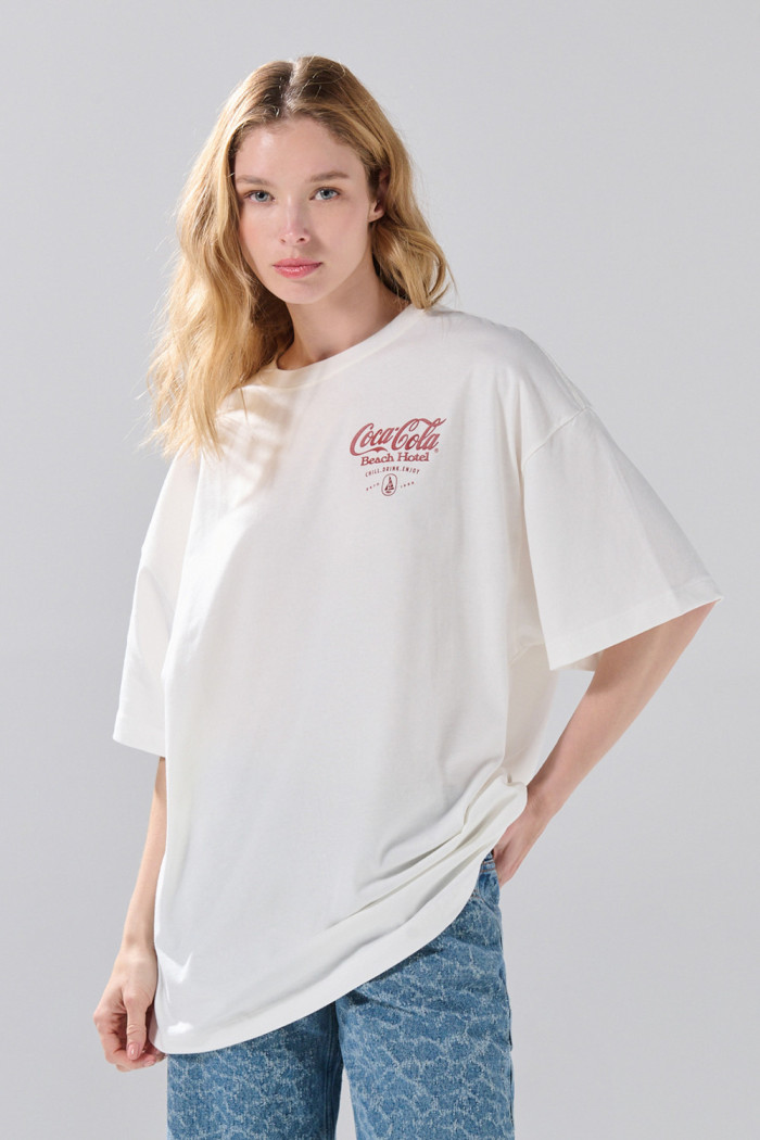 Camiseta oversize manga corta crema con arte de Coca-Cola
