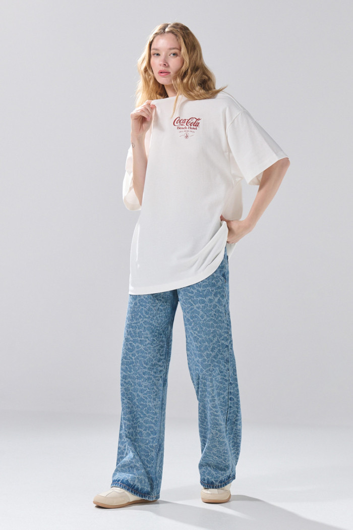 Camiseta oversize manga corta crema con arte de Coca-Cola
