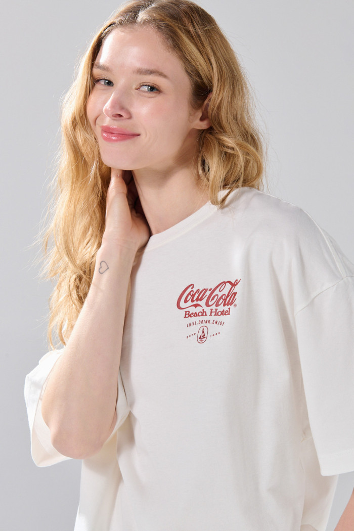 Camiseta oversize manga corta crema con arte de Coca-Cola
