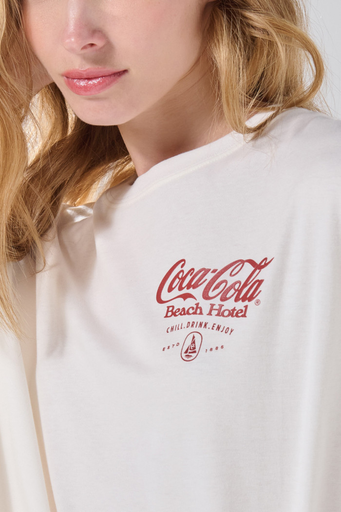 Camiseta oversize manga corta crema con arte de Coca-Cola
