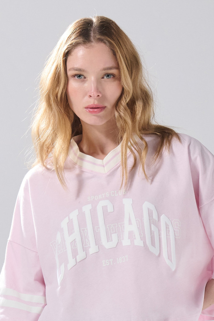 Camiseta crop top rosada oversize college con cuello V

