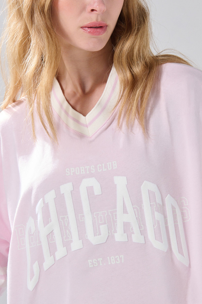 Camiseta crop top rosada oversize college con cuello V
