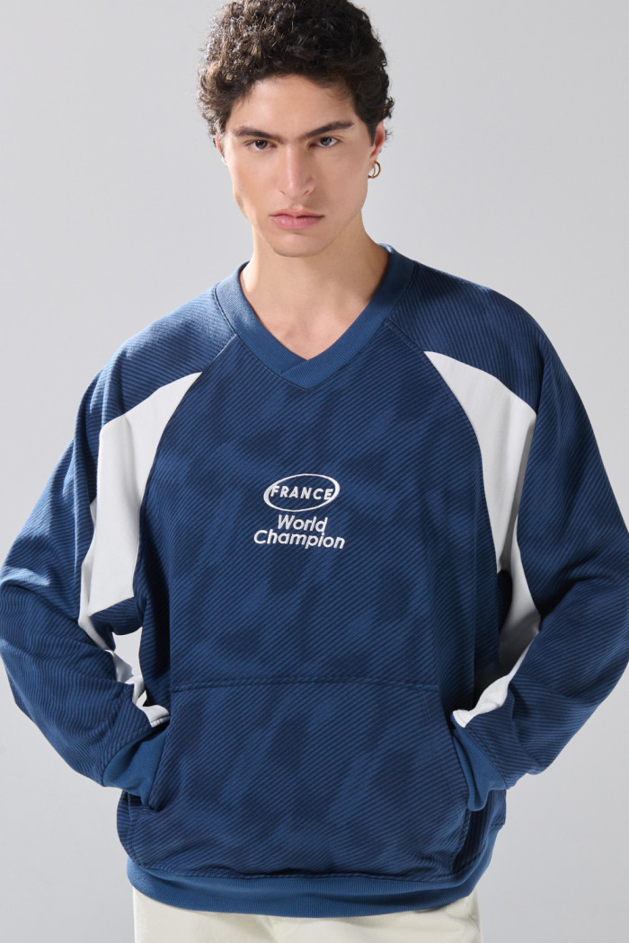 Buzo cuello V oversize azul con arte college de Fan Edition
