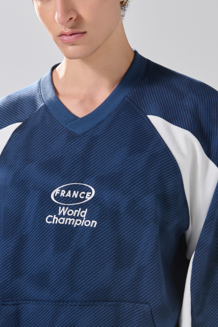 Buzo cuello V oversize azul con arte college de Fan Edition
