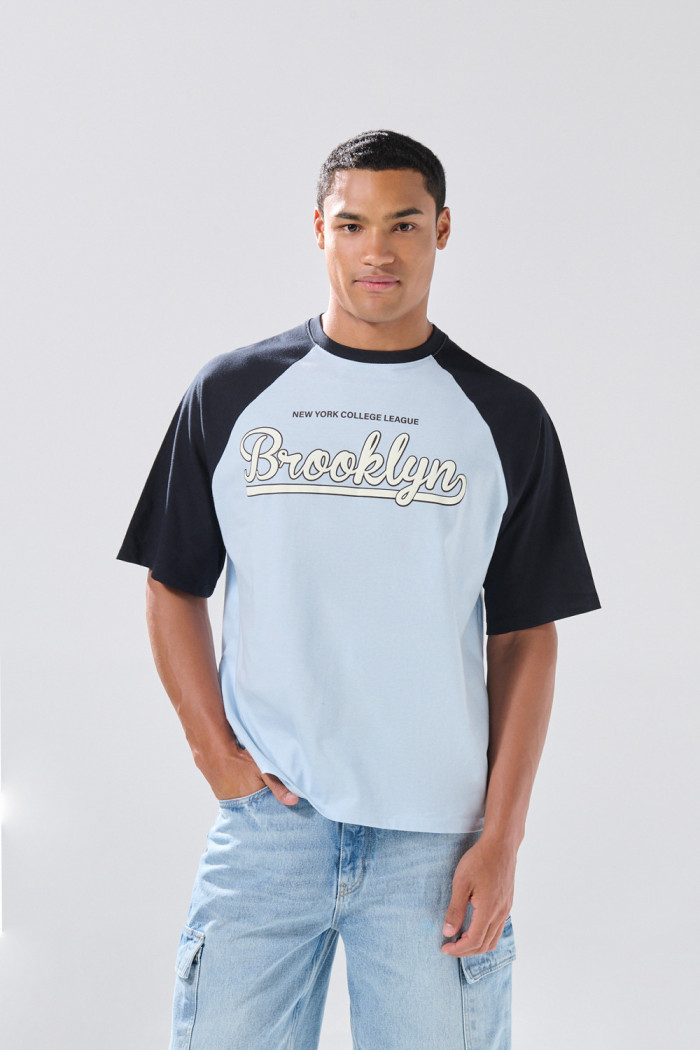 Camiseta azul clara manga ranglan con texto college
