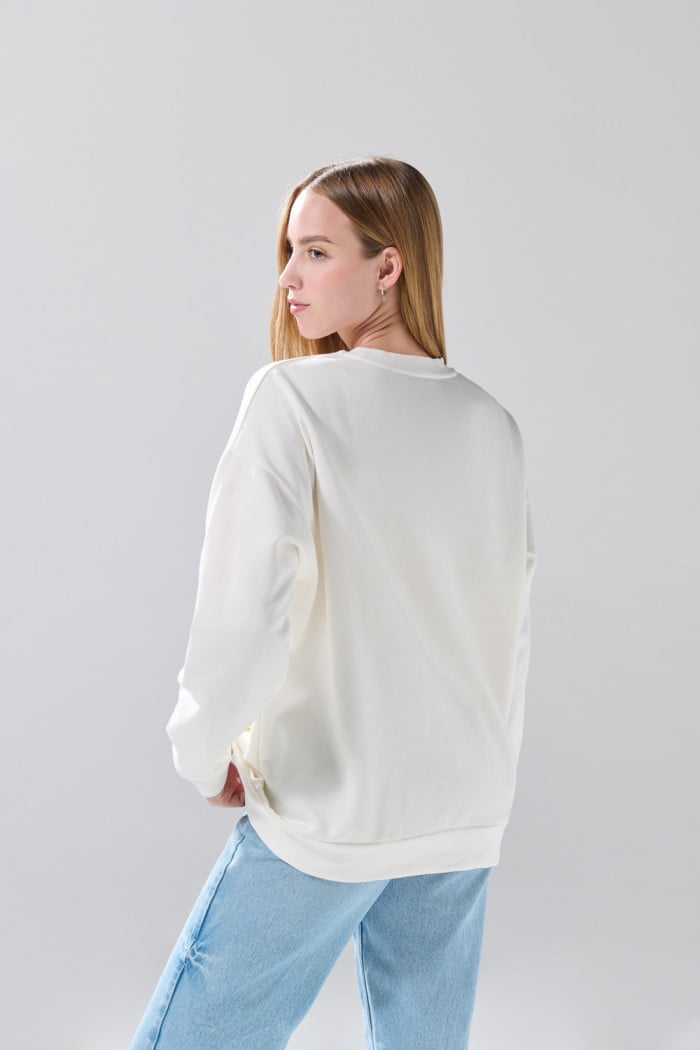 Buzo oversize cuello redondo crema con arte de Snoopy
