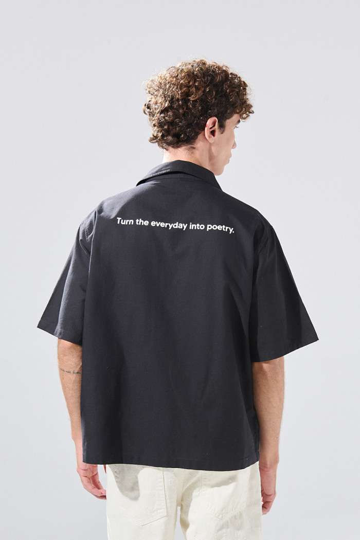 Camisa negra con cuello resort, botones y texto de Poetry
