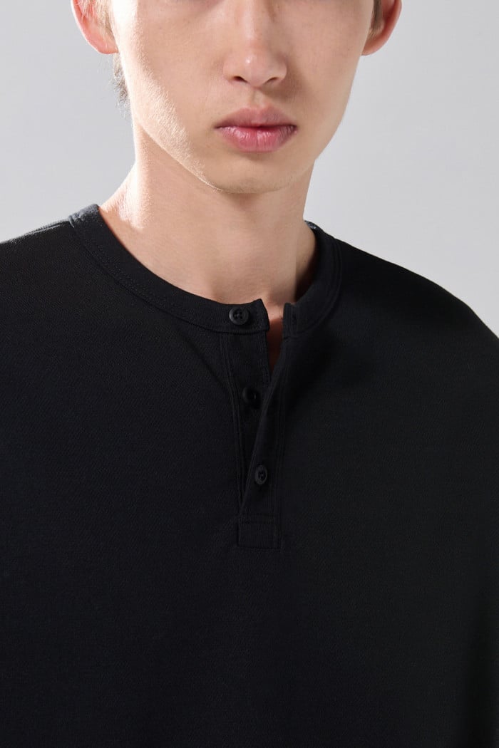 Camiseta cuello redondo unicolor con botones visibles

