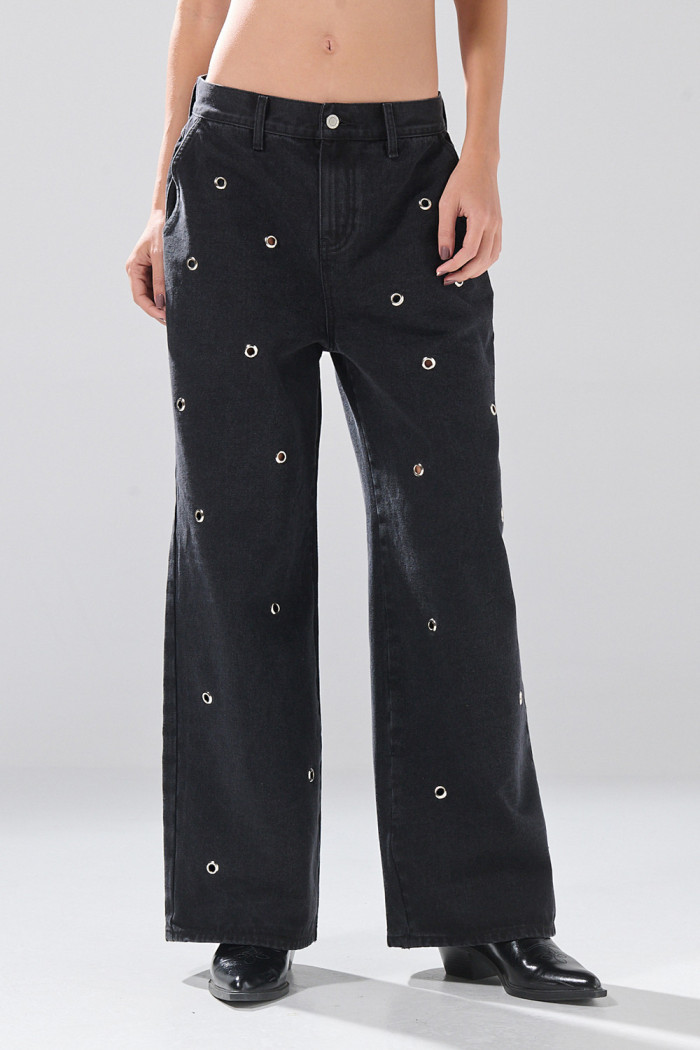 Jean skater gris intenso con ojaletes metálicos y bota ancha
