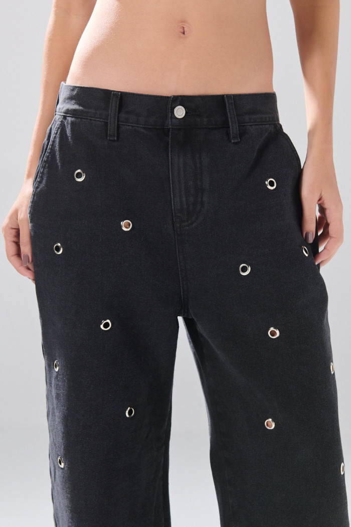 Jean skater gris intenso con ojaletes metálicos y bota ancha
