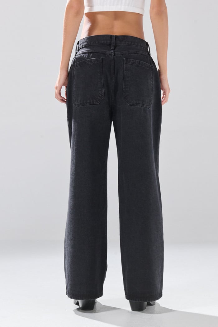Jean skater gris intenso con ojaletes metálicos y bota ancha
