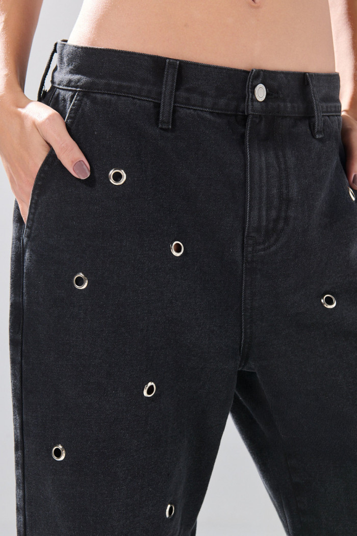 Jean skater gris intenso con ojaletes metálicos y bota ancha

