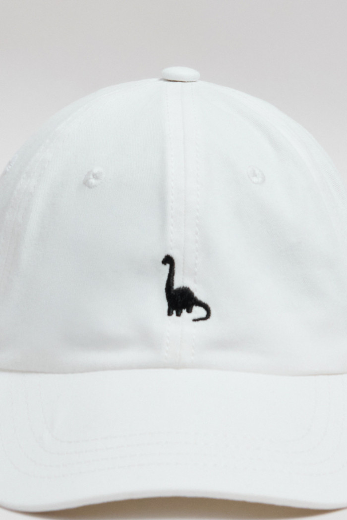 Cachucha beisbolera crema con bordado de dinosaurio