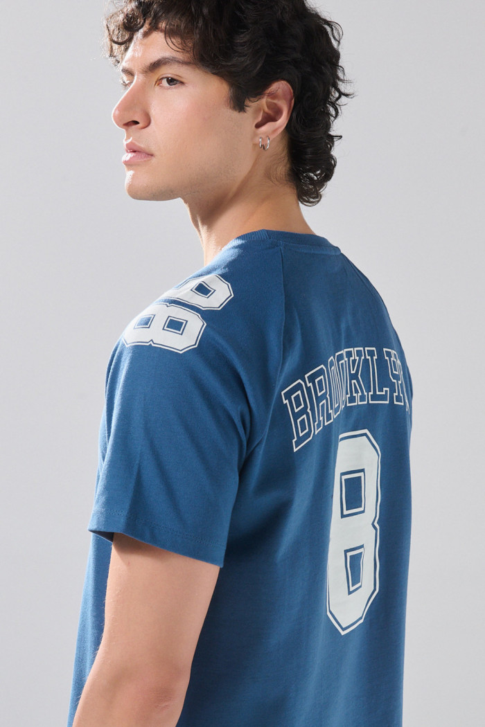 Camiseta azul con manga ranglan y diseños college
