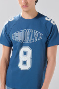 Camiseta azul con manga ranglan y diseños college
