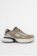 Tenis chunky color kaki con paneles en contraste negro y crema.